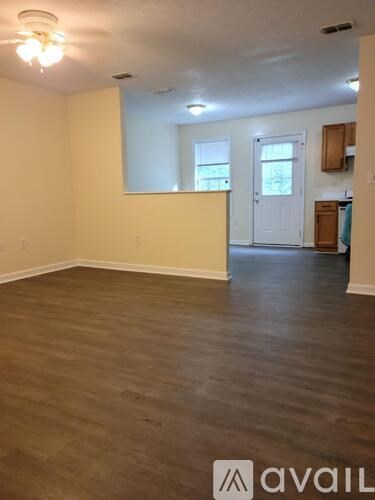 A room with wooden flooring and a white wall with a window.