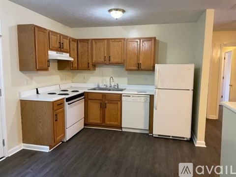 A kitchen with white appliances and wooden cabinets.