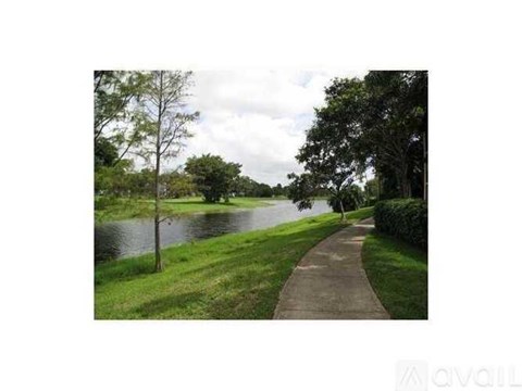 A pathway runs alongside a body of water with trees on the side.