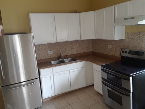 A kitchen with a stainless steel refrigerator, oven, and sink.