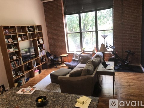 A living room with a couch, a coffee table, and a bookshelf filled with books.