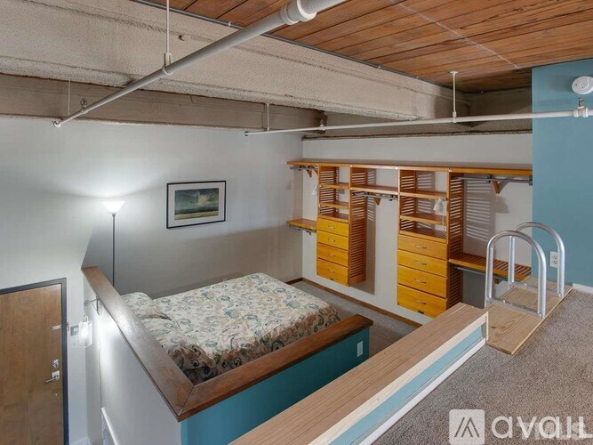 A bedroom with a bed, a dresser, and a small framed picture on the wall.
