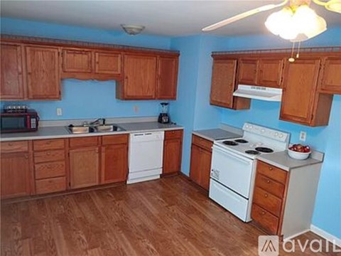 A kitchen with wooden cabinets and a white stove top oven.
