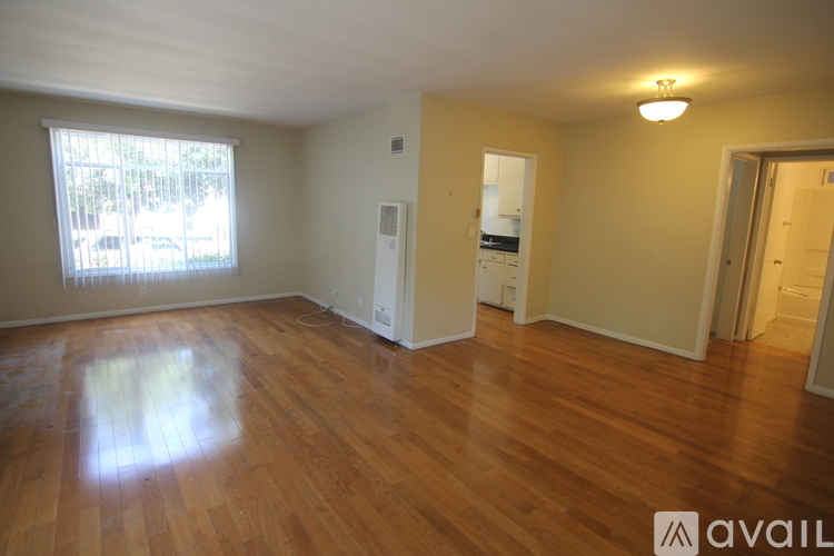 A room with wooden floors and a window letting in natural light.
