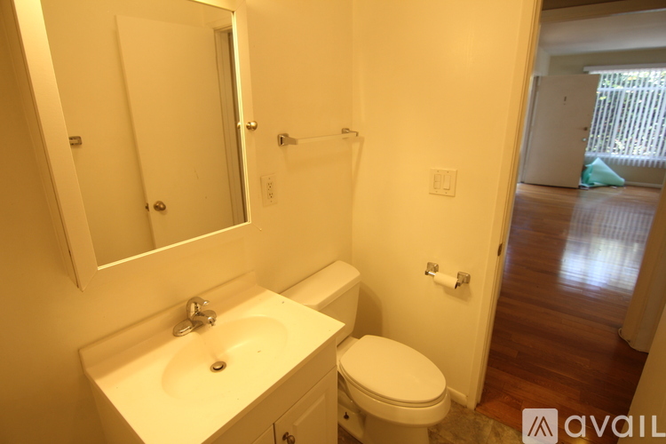 A bathroom with a toilet, sink, and mirror.