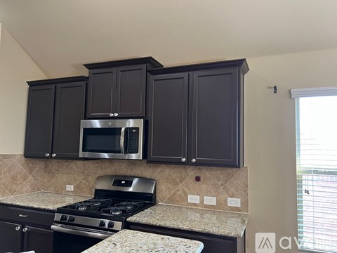 A kitchen with black cabinets and a stove top oven.