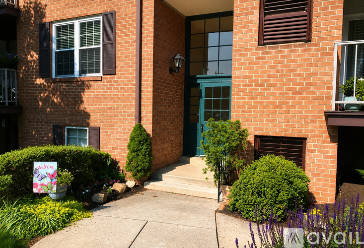 A red brick house with a blue door and a sign that says "available".
