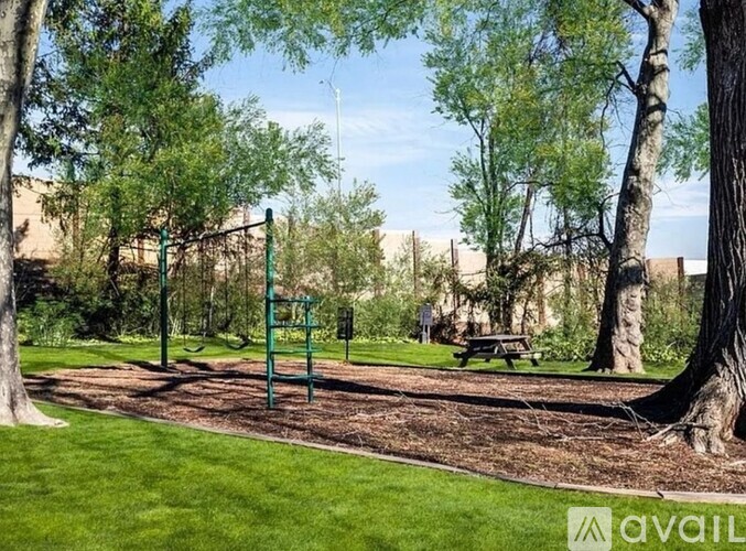 A playground with a swing set and picnic table in a park.