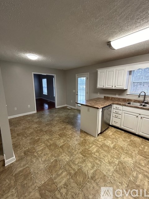 A kitchen with white cabinets and a tiled floor.