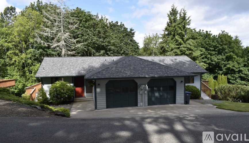 A house with a grey roof and a garage door is for sale.