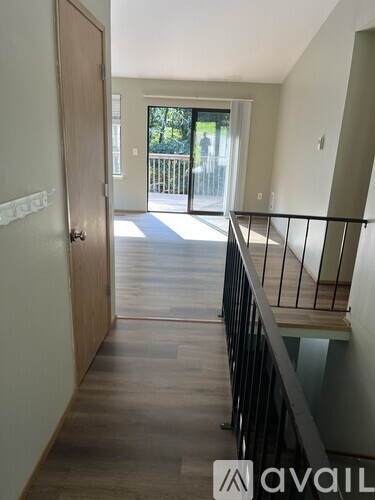 A hallway with a wooden floor and a black railing.