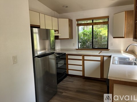 A kitchen with a black refrigerator and wooden cabinets.