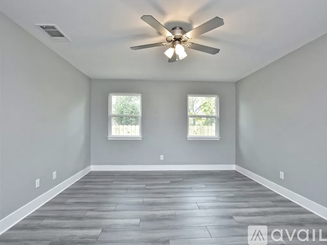 A room with a ceiling fan and two windows.