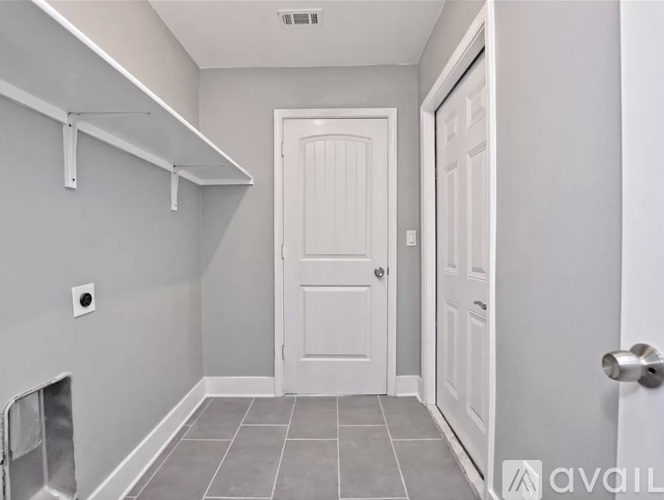 A white door is in a hallway with a grey floor.