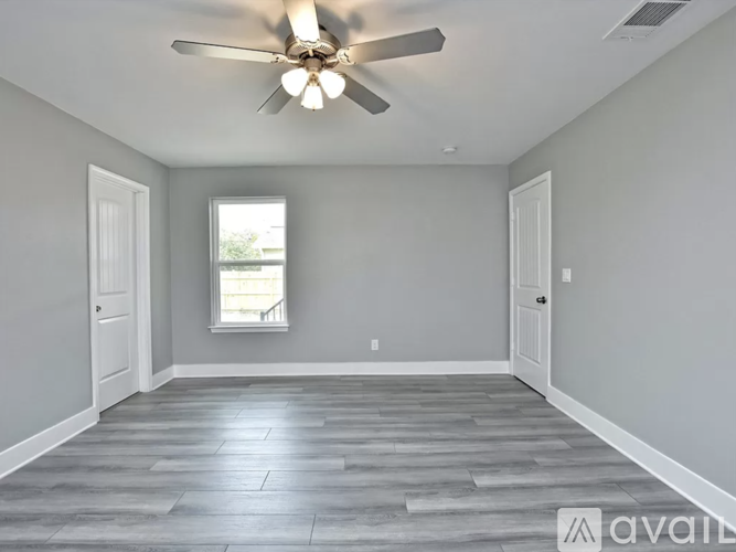 A spacious room with a ceiling fan and wooden flooring.