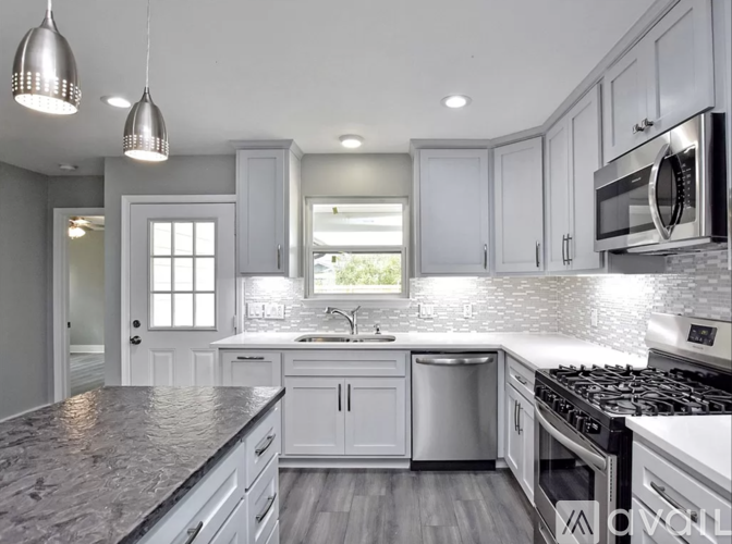A modern kitchen with white cabinets and a granite countertop.