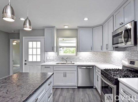 A modern kitchen with white cabinets and a granite countertop.