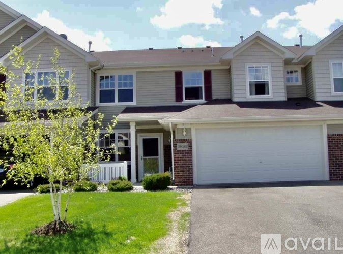A two-story house with a garage and a tree in front.