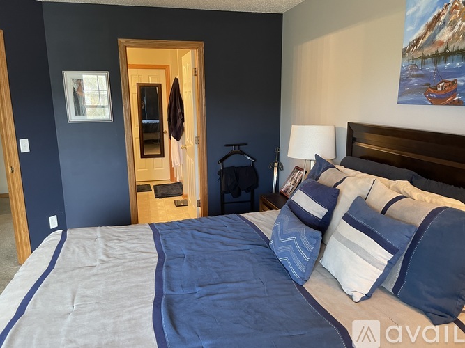 A bedroom with a bed, pillows, and a painting on the wall.