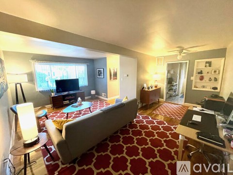 A living room with a grey couch and a red carpet.
