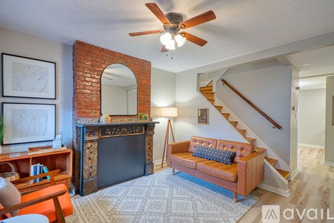 A living room with a brick fireplace and a brown couch.