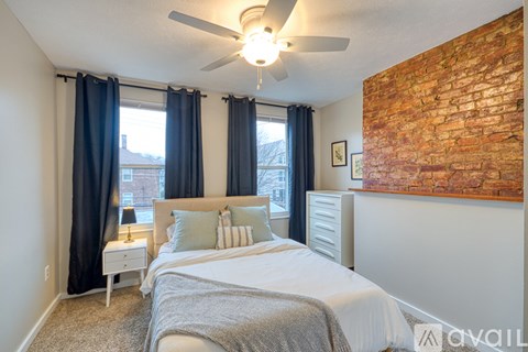 A bedroom with a brick wall on one side and a bed in the center.