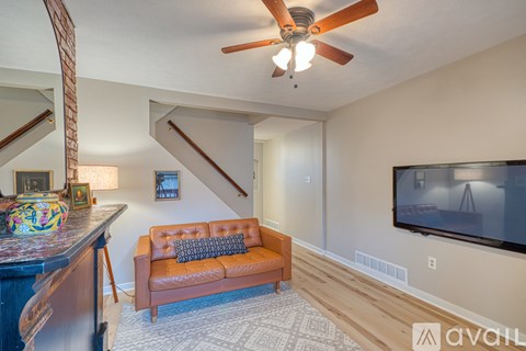 A living room with a brown couch and a ceiling fan.