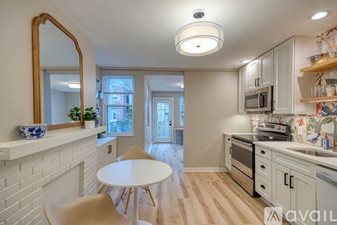 A kitchen with a white table and chairs, a white brick wall, and a large mirror.