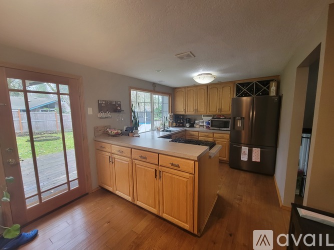 A kitchen with wooden cabinets and a black fridge.