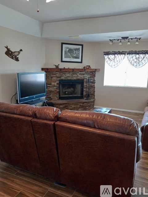 A living room with a brown couch and a fireplace.