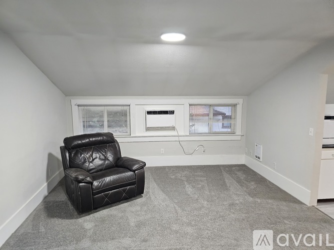 A black leather chair is placed in a room with a grey carpet.