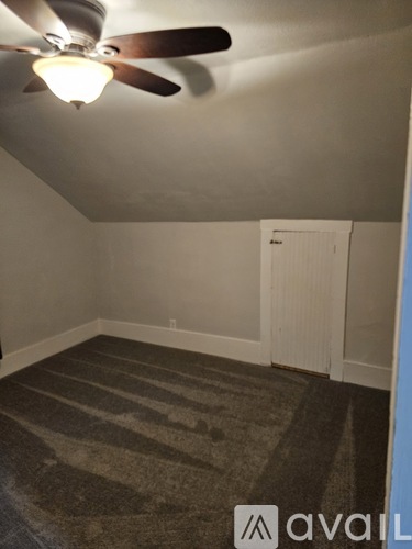 A room with a ceiling fan and striped carpet.
