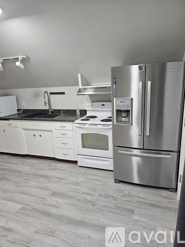 A kitchen with a stainless steel refrigerator and white appliances.