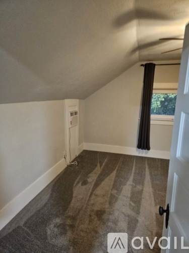 A room with a carpeted floor and a window with black curtains.