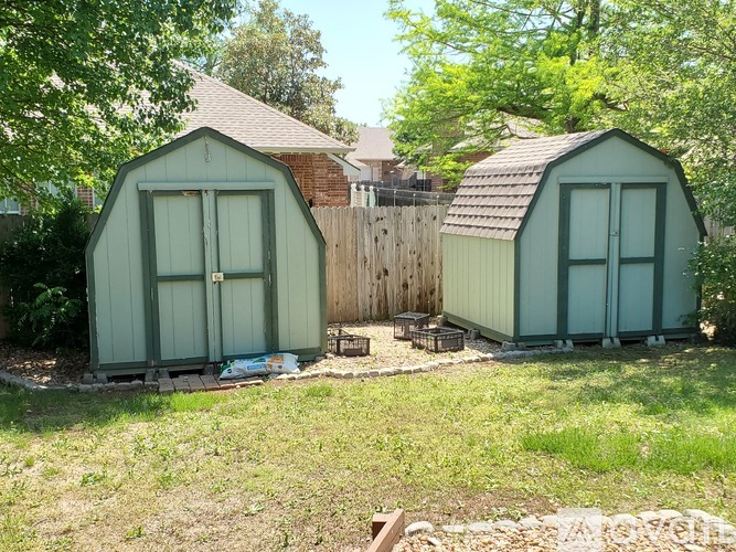 Two green sheds are situated in a grassy area.