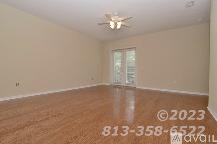 A room with a ceiling fan and wooden flooring.