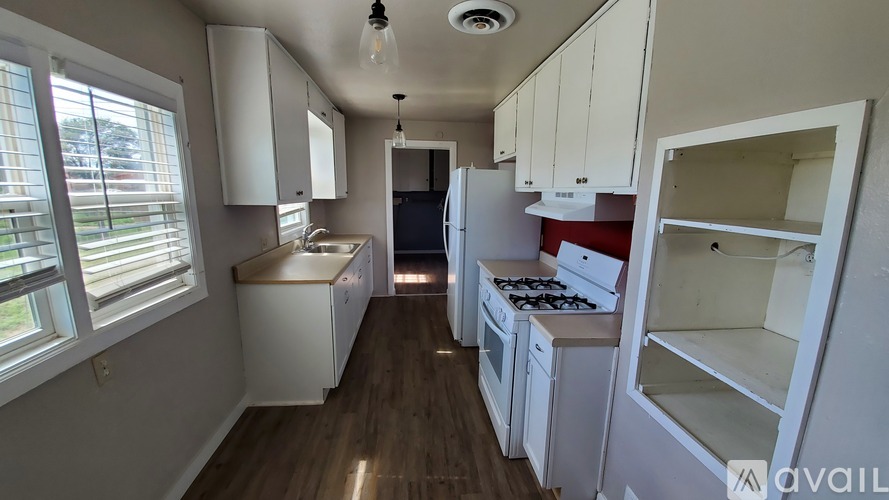 A kitchen with white cabinets and a wooden floor.