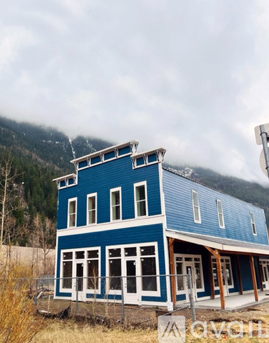 A blue house with white trim and a mountain in the background.