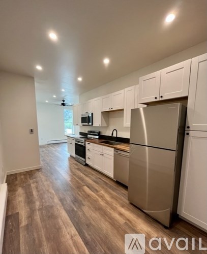 A kitchen with white cabinets and a stainless steel refrigerator.
