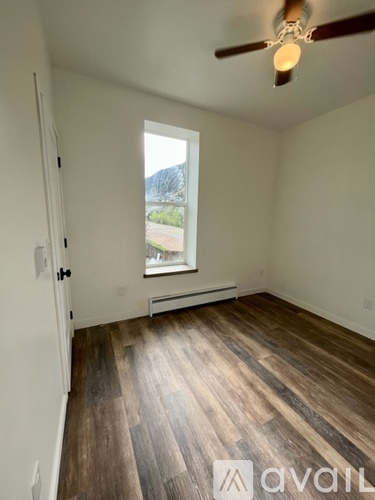 A room with wooden flooring and a window overlooking a street.