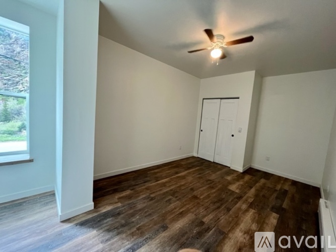 A room with a ceiling fan and wooden flooring.