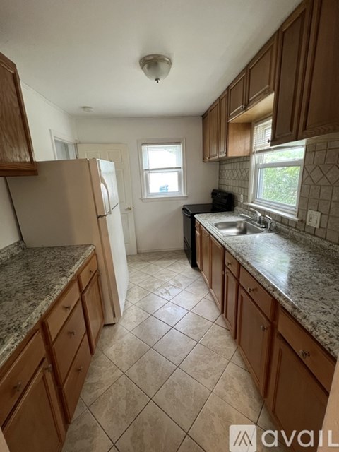 A kitchen with brown cabinets and a marble countertop.