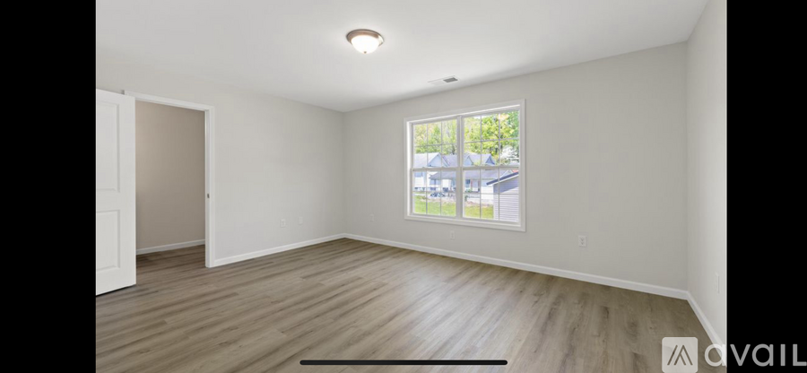 A room with a window showing a view of a building and trees outside.
