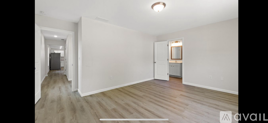 A spacious room with wooden flooring and white walls.