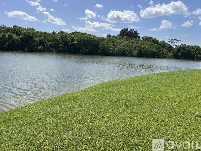 A grassy area borders a body of water with a tree-covered island in the distance.