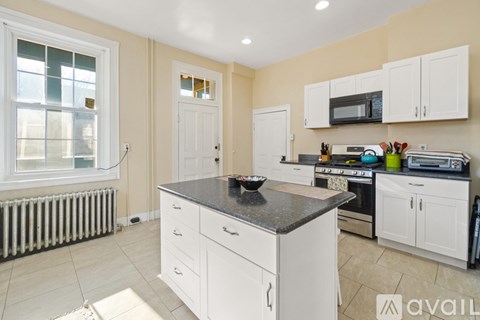 A kitchen with white cabinets and a black countertop.