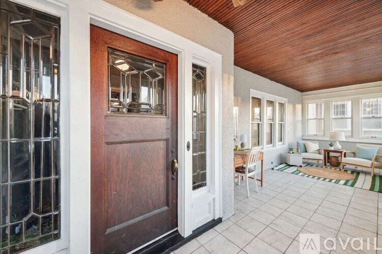 A wooden door with a glass window is in the middle of a room with a tiled floor.