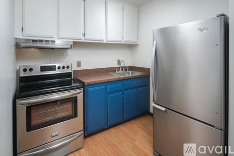 A kitchen with a stainless steel refrigerator, a stove, and blue cabinets.