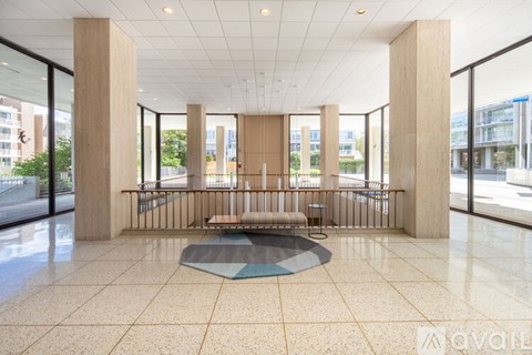 A spacious lobby with a bench and a circular rug in the middle.