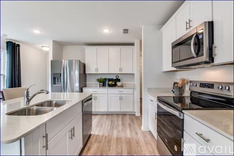 A modern kitchen with white cabinets and stainless steel appliances.